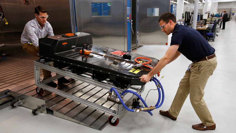 People remove a Chevrolet Bolt EV battery pack for testing