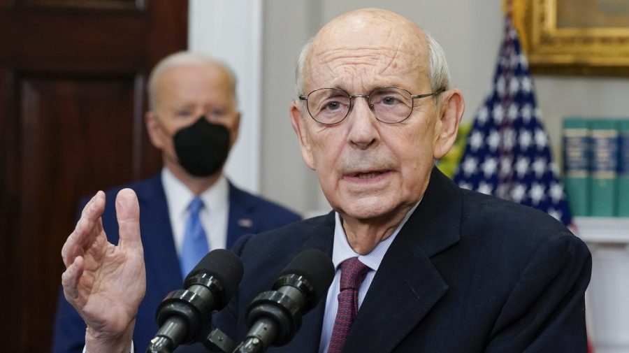 President Biden stands in the background while Supreme Court Justice Stephen Breyer announces his retirement in a press conference.