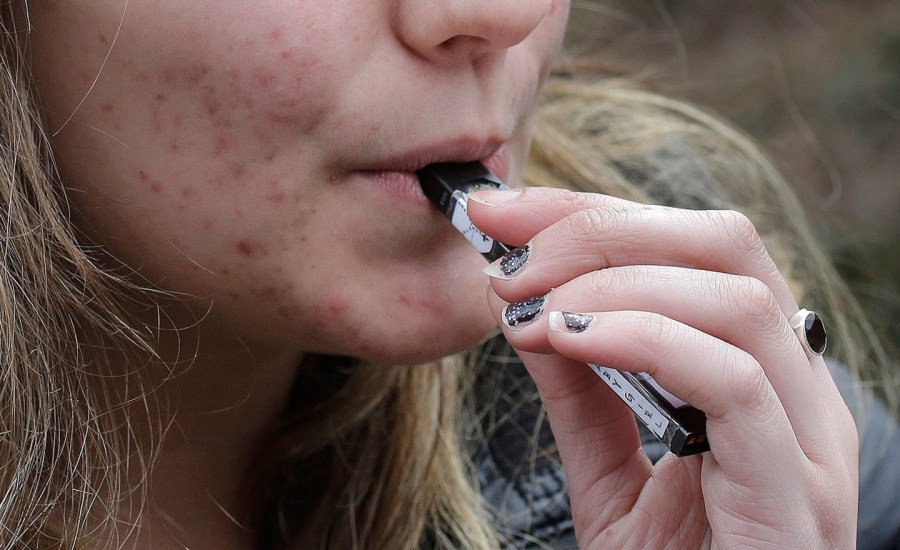 A teenager smokes a vaping device.