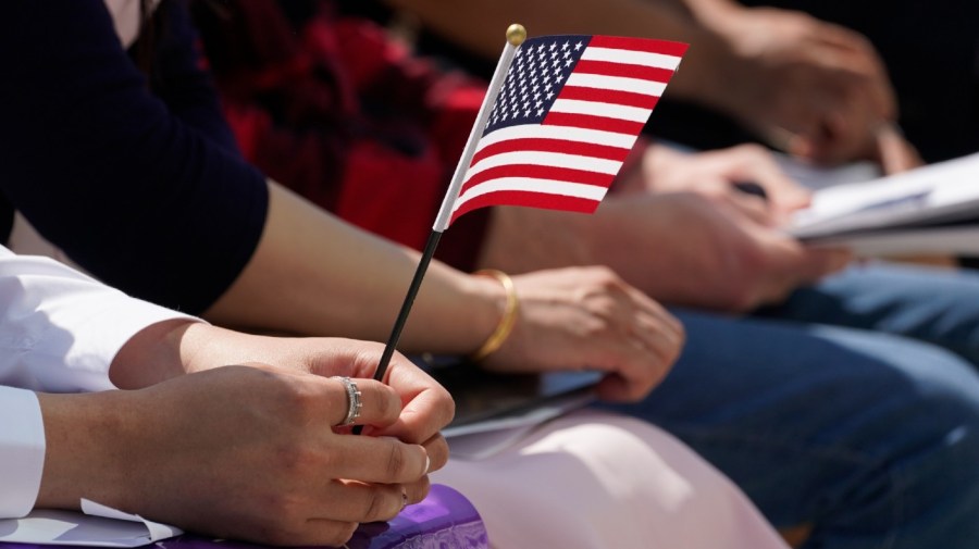 A new citizen holds the America flag during a Naturalization Ceremony at Indianapolis Motor Speedway, Tuesday, May 17, 2022, in Indianapolis.