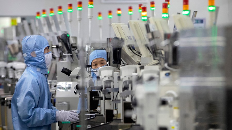 Employees wearing protective equipment work at a semiconductor production facility