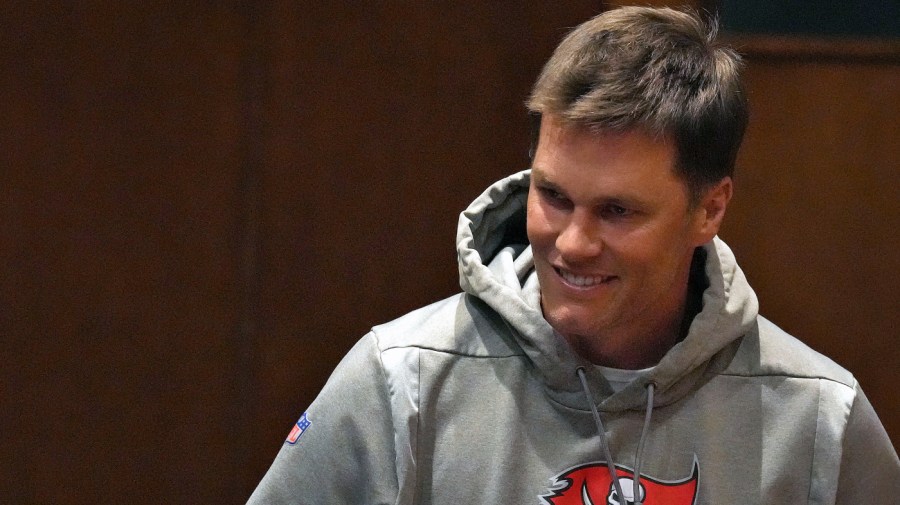 Tampa Bay Buccaneers quarterback Tom Brady smiles as he arrives for a news conference for new head coach Todd Bowles.