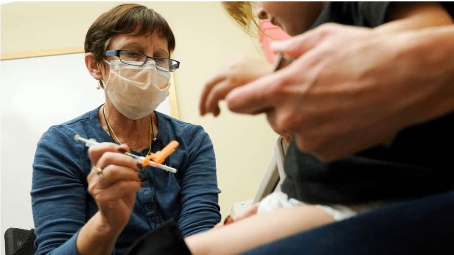 Deborah Sampson, left, a nurse at a University of Washington Medical Center clinic in Seattle, gives a Pfizer COVID-19 vaccine shot to a 20-month-old child, Tuesday, June 21, 2022, in Seattle.