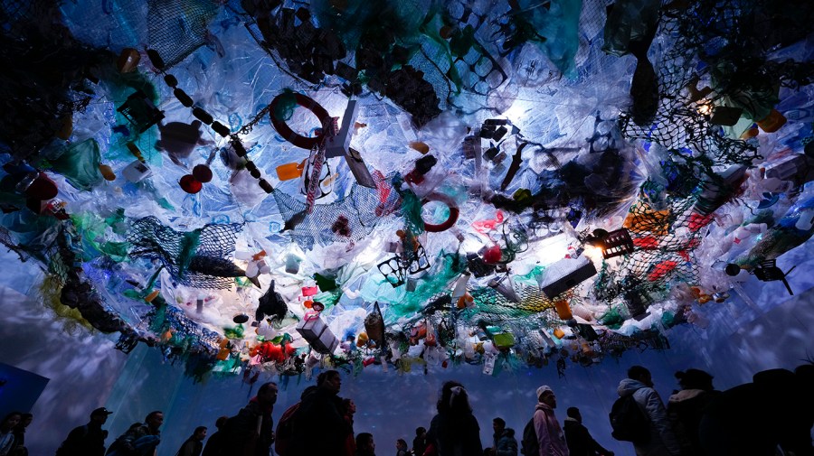 People walk in an exhibit simulating sea pollution