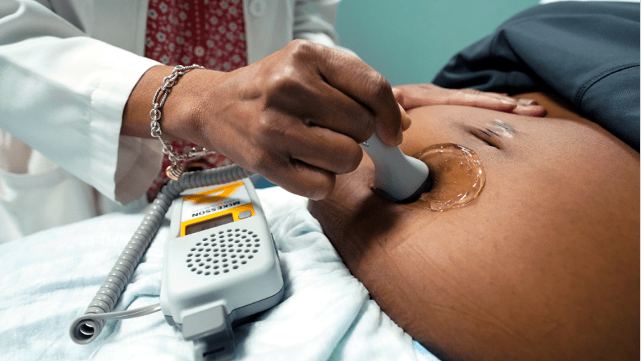 Dr. Felecia Brown, a midwife at Sisters in Birth, a Jackson, Miss., clinic that serves pregnant women, left, uses a hand-held Doppler probe on Kamiko Farris, of Yazoo City, to measure the heartbeat of the fetus, Dec. 17, 2021.