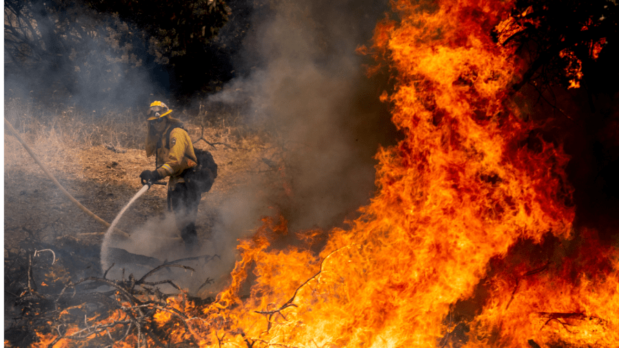 A firefighter sprays water while battling the Oak Fire in Mariposa County, Calif., on Saturday, July 23, 2022.