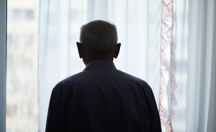 A man looking out a window alone.