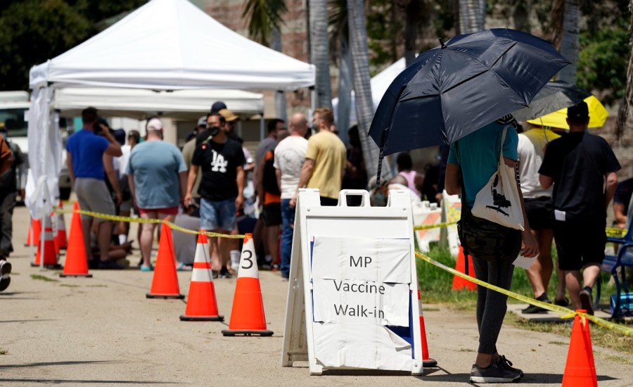 people waiting outside, sign saying MP vaccine walk in