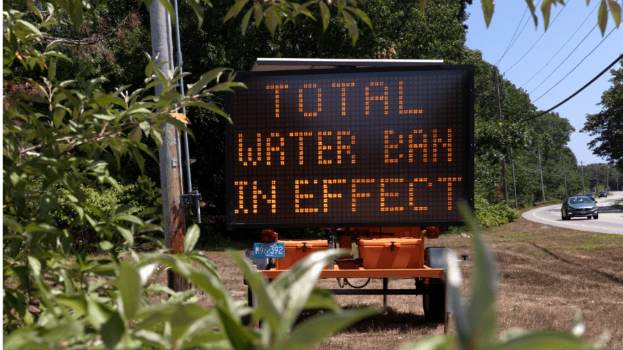 A sign announces a water ban, Saturday, Aug. 6, 2022, in Scituate, Mass.