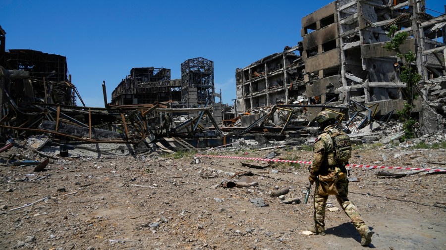 A Russian soldier walks in front of the damaged Metallurgical Combine Azovstal plant, in Mariupol.