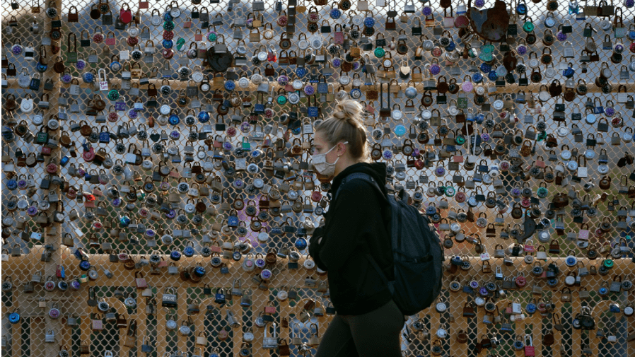 FILE - Locks cover the fence on the Love Bridge in the Oakland neighborhood of Pittsburgh as a person walks by Nov. 3, 2021.