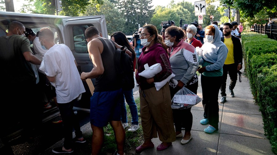 Migrants from Venezuela wait to board a bus