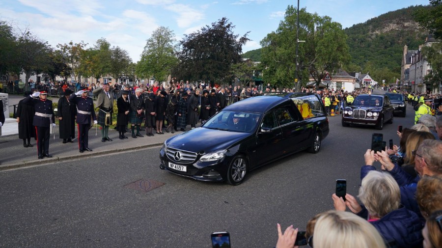 Members of the public line the streets in Ballater, Scotland, as the hearse carrying the coffin of Queen Elizabeth II passes through as it makes its journey to Edinburgh from Balmoral in Scotland, Sunday, Sept. 11, 2022.