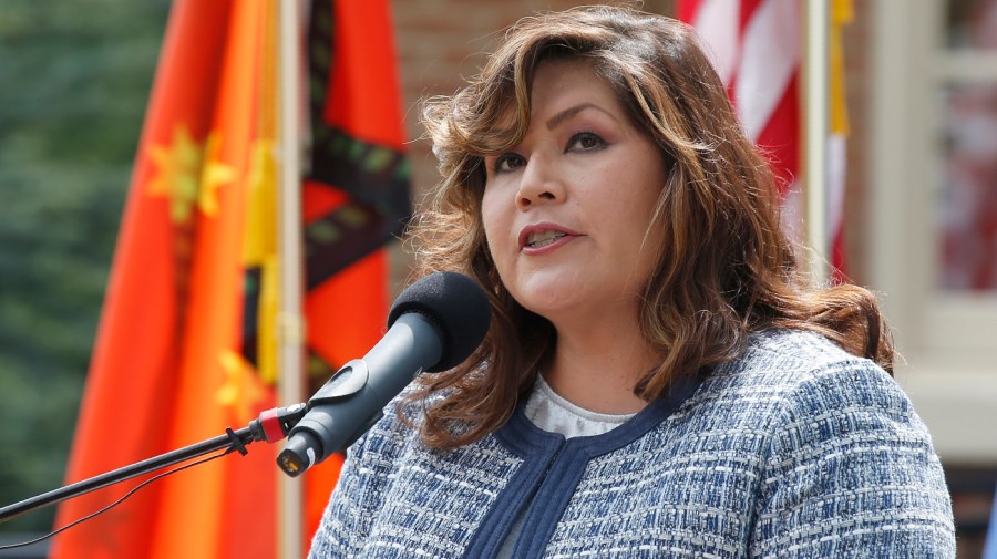 Kimberly Teehee speaks in front of the flag of the Cherokee Nation