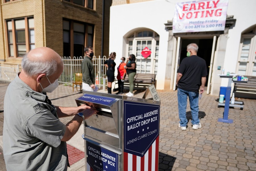 A voter submits a ballot in an official drop box during early voting in Athens, Ga., on Oct. 19, 2020.