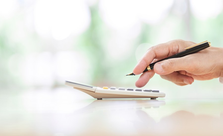 Person using calculator, holding pen.