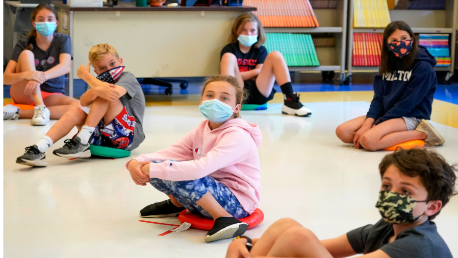 FILE - Fifth graders wearing face masks sit at proper social distancing during a music class at the Milton Elementary School in Rye, N.Y., May 18, 2021.