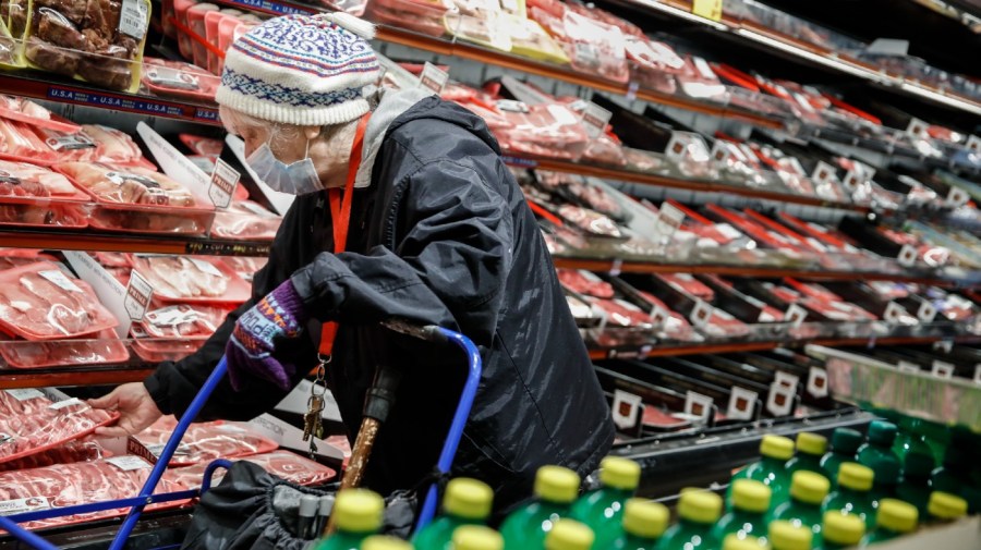 FILE - An elderly shopper wears personal protective equipment as she browses the meat section of a grocery store on April 18, 2020, in the Harlem neighborhood of the Manhattan borough of New York.