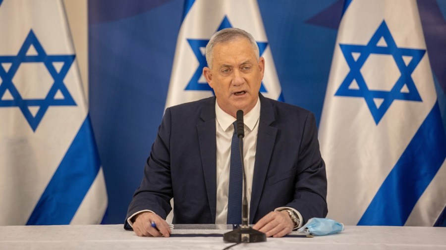 Benny Gantz gives a speech in front of Israeli flags.