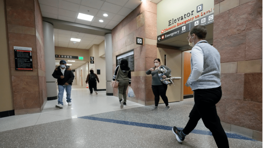 Workers and patients move down one of the main hallways at UCHealth University of Colorado hospital Friday, April 1, 2022, in Aurora, Colo.