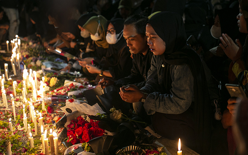 A woman weeps during a candlelight vigil for the victims of Saturday's soccer stampede