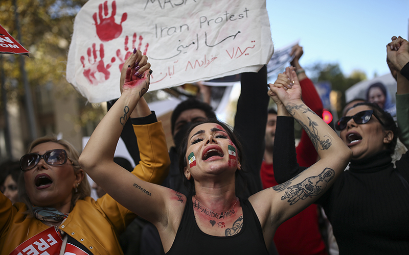 Iranian women holding signs and in facepaint depicting the Iranian flag shout slogans to protest over the death of Mahsa Amini in Istanbul, Turkey