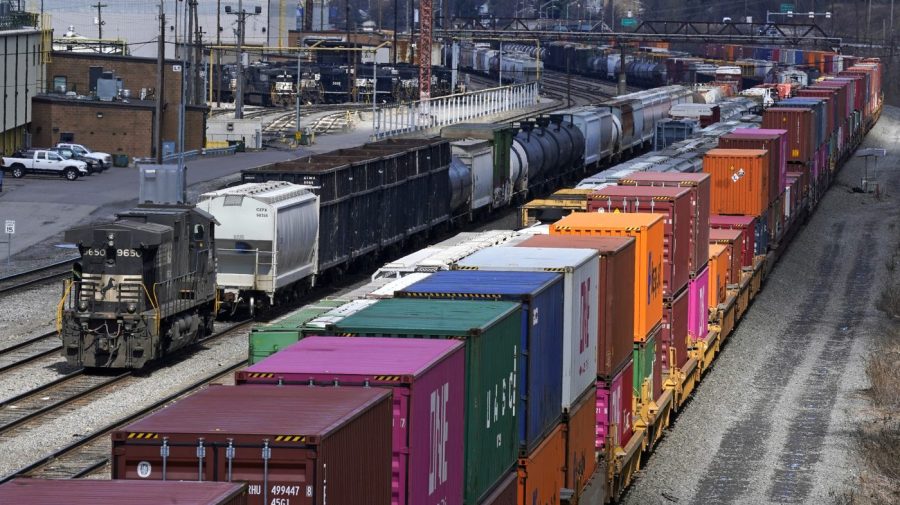 Colorful containers are seen stacked on a freight train at a rail yard.