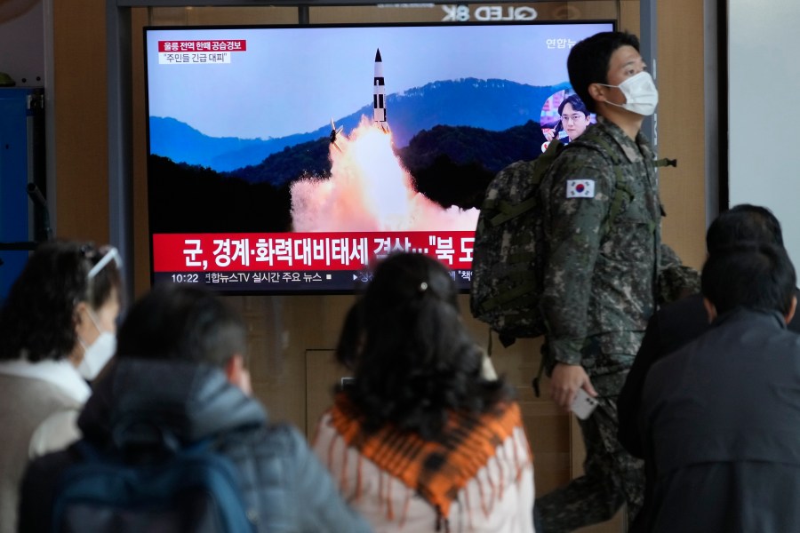 A South Korean army soldier passes by a TV screen showing a file image of North Korea's missile launch