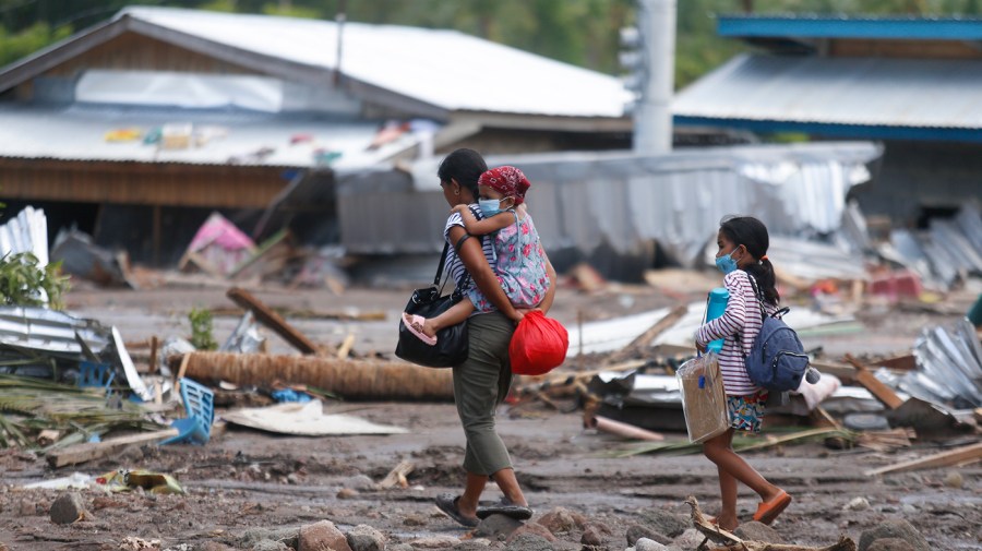 Residents walk past damaged homes in the southern Philippines