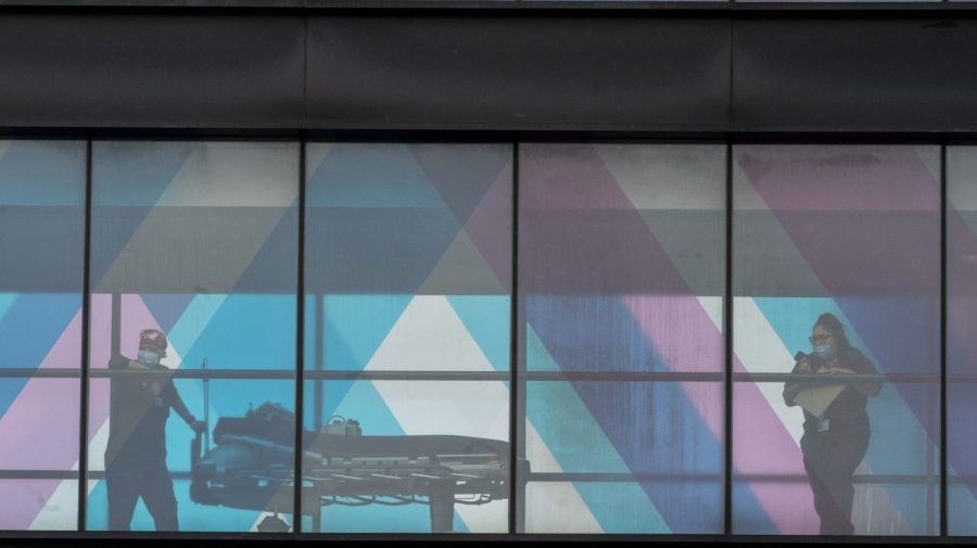 Health care workers look out the window at NY Presbyterian and Mount Sinai from an overpass at Mount Sinai Hospital, Tuesday, March 16, 2021, in New York.