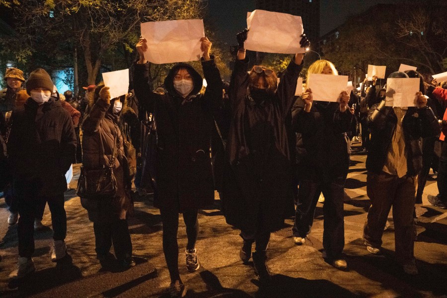 Protesters hold up blank papers and chant slogans