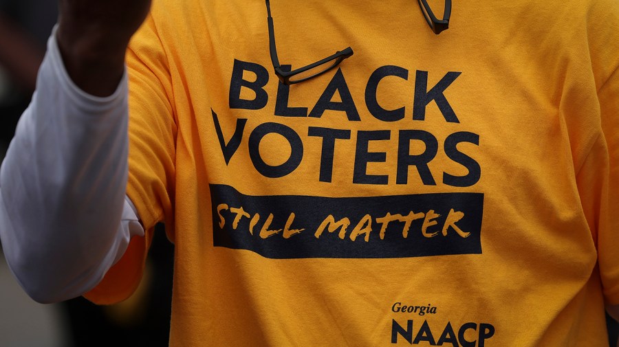 A Warnock supporter wears a yellow shirt that reads, "Black voters still matter" with Georgia NAACP logo at the bottom