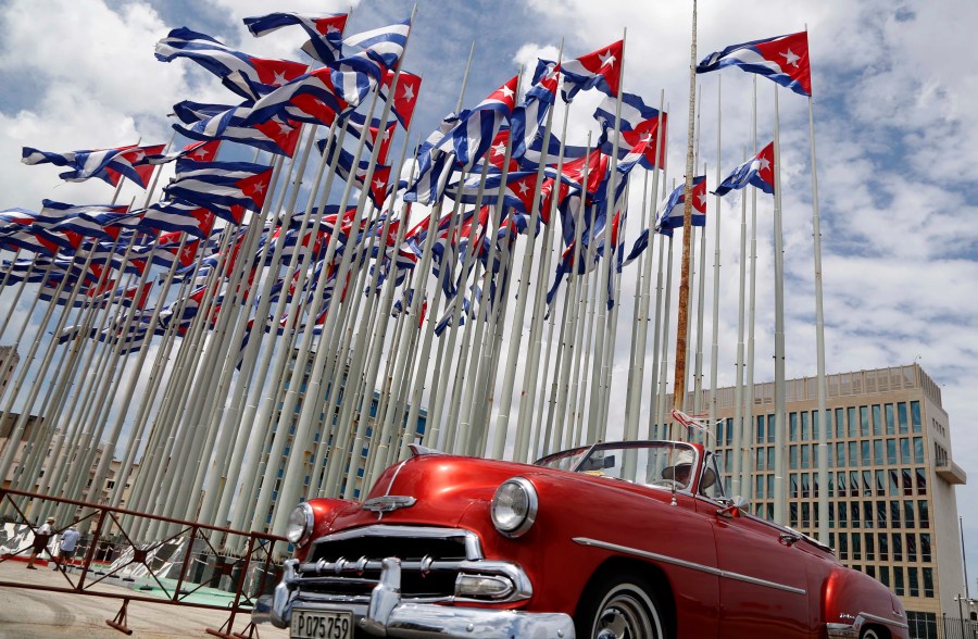 A classic American convertible car passes beside the United States Embassy as Cuban flags fly at the Anti-Imperialist Tribune, a massive stage on the Malecon seaside promenade in Havana, Cuba, July 26, 2015.