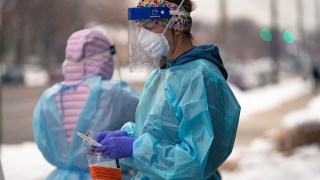 A nurse prepares for a COVID-19 test outside the Salt Lake County Health Department