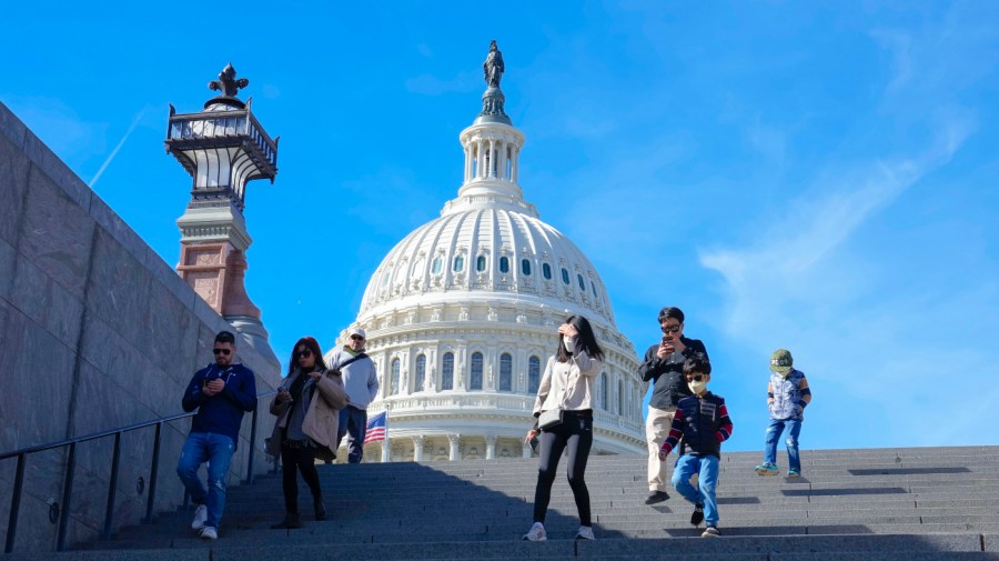 People walk down steps with the Capitol in the background.