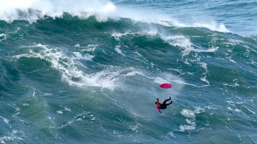 A surfer crashes while riding a wave at Praia do Norte