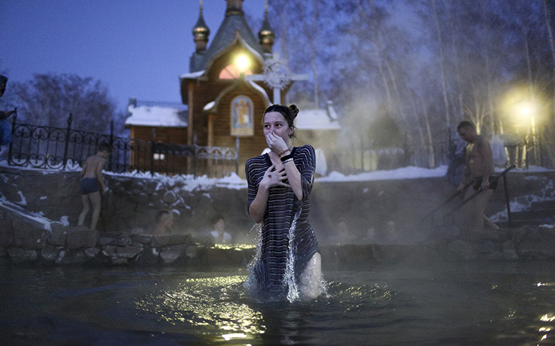 A woman bathes in water during a traditional Epiphany celebration