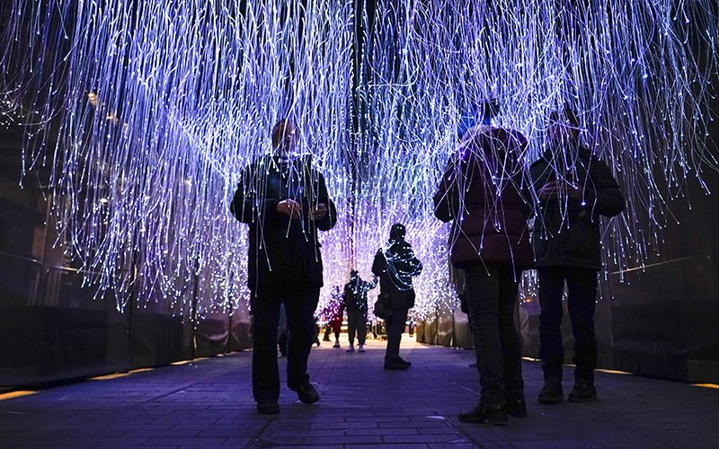 People walk through an installation of more than 3,000 fiber optic threads