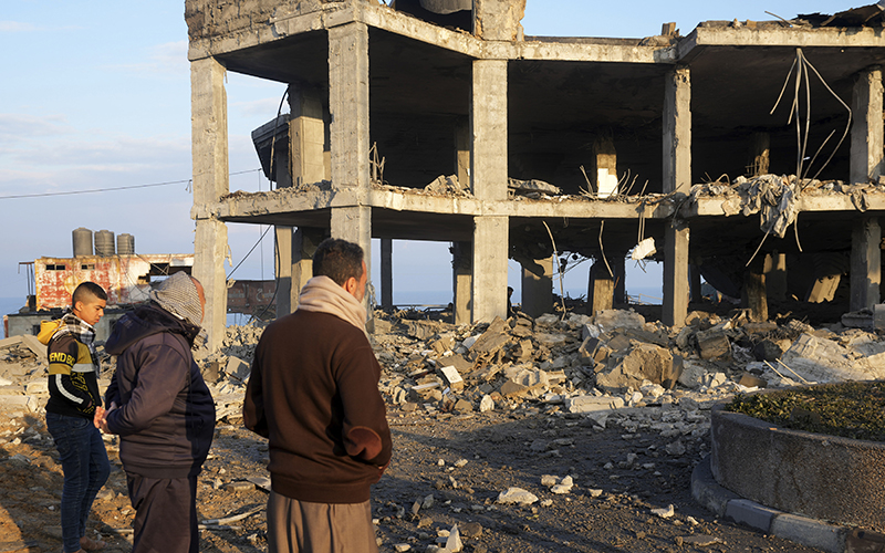 People view the rubble of a destroyed building hit by Israeli airstrikes in Gaza City