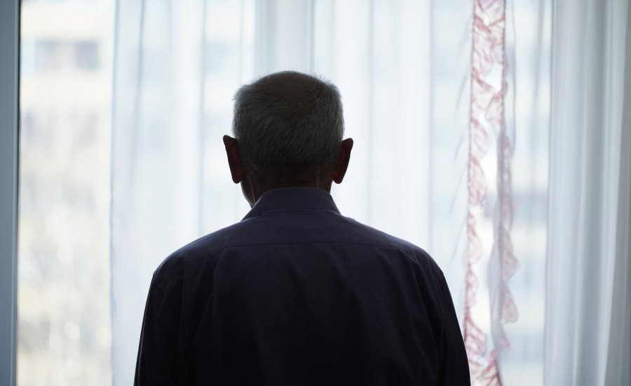 Older man looking out of window.