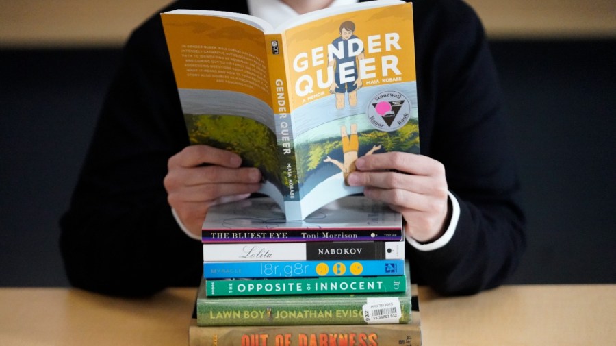 Amanda Darrow, director of youth, family and education programs at the Utah Pride Center, poses with books that have been the subject of complaints from parents in Salt Lake City on Dec. 16, 2021.