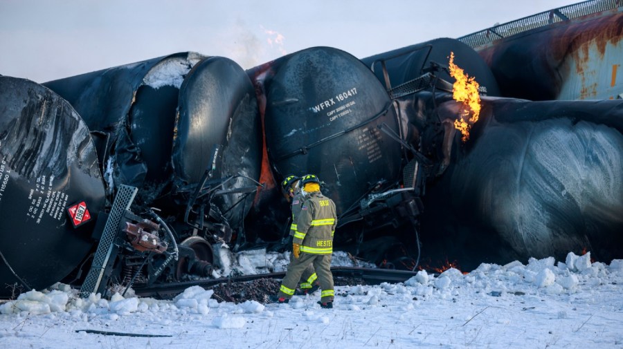 Firefighters work near piled up train cars, near Raymond, Minn., Thursday, March 30, 2023, the morning after a BNSF freight train derailed. Authorities say a train hauling ethanol and corn syrup derailed and caught fire and residents within 1/2 mile of the crash were ordered to evacuate from their homes.