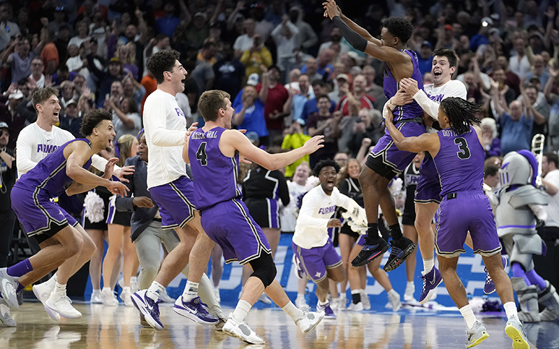 Furman guard JP Pegues, third from right, celebrates with the team after defeating Virginia in a first-round college basketball game