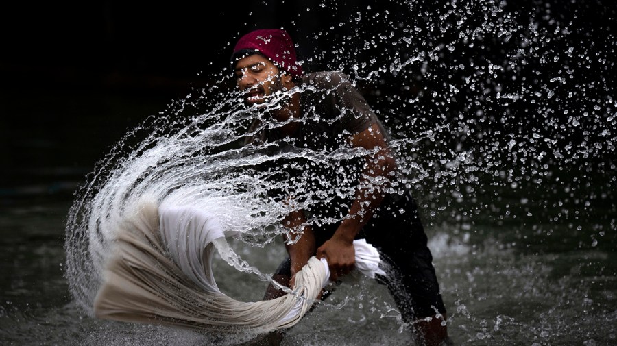 A washerman washes clothes on the banks of the river Brahmaputra in Guwahati, India