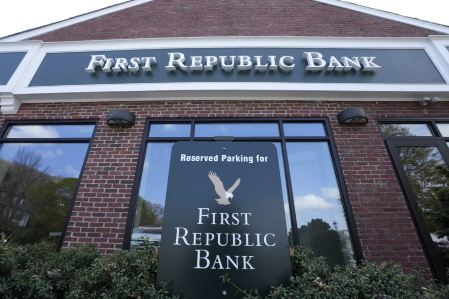 First Republic Bank signs and logos rest near a parking space, below, and on the exterior of a bank branch location, above, Wednesday, April 26, 2023, in Wellesley, Mass. First Republic Bank's stock continued to slide Wednesday, an ongoing rout that has erased much of its value just this week on concerns about the bank's financial health in the wake of two other bank collapses. (AP Photo/Steven Senne)