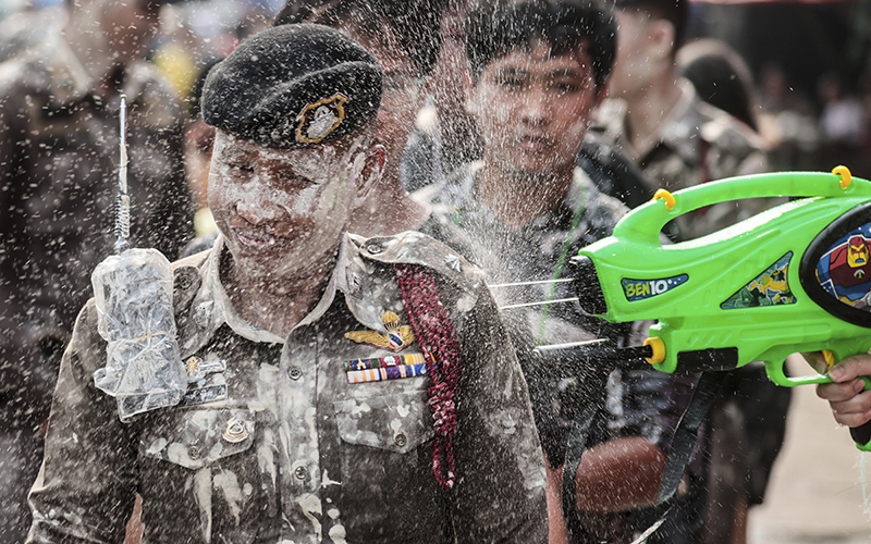 A man sprays colored water at a policeman to celebrate Songkran festival