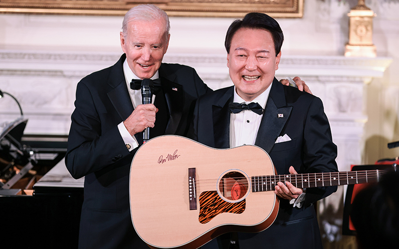 South Korean President Yoon Suk Yeol holds up an acoustic guitar as President Biden speaks