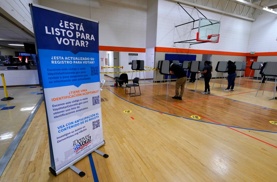 FILE - A sign in Spanish stands near voters as they cast their ballots at stations inside the La Familia Recreation Center in the Baker neighborhood Nov. 3, 2020, south of downtown Denver.