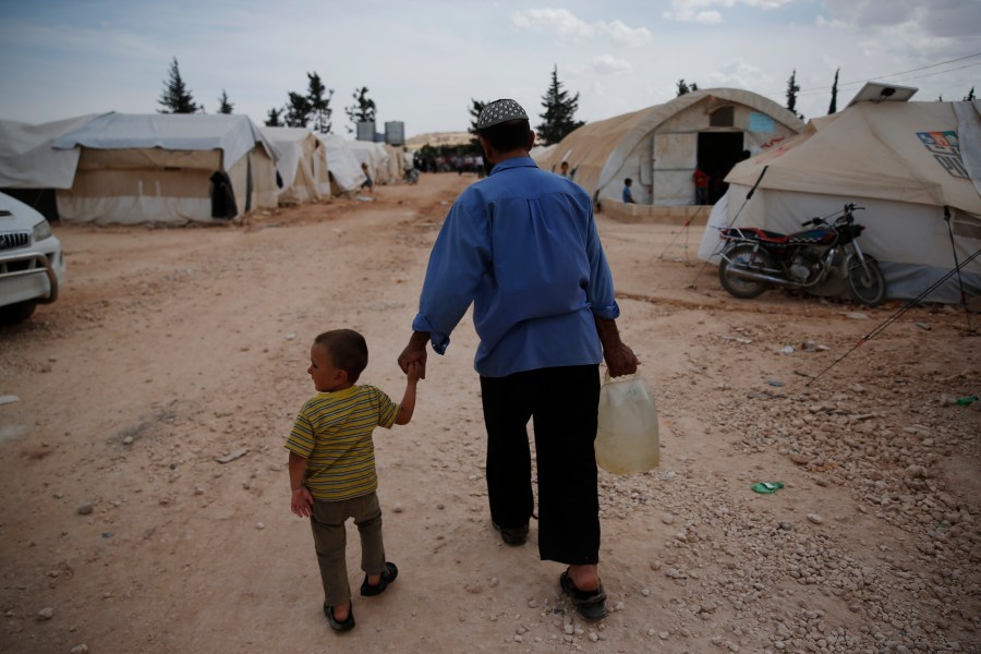 FILE - Syrians walk in a camp for internally displaced people in al-Bab, northern Syria, on May 29, 2018. The war in Ukraine helped push the global total of people left internally displaced by conflict or natural disasters to a record high of 71.1 million last year, according to a report released Thursday May 11, 2023. Syria had 6.8 million displaced by conflict after more than a decade of civil war. (AP Photo/Lefteris Pitarakis, File)