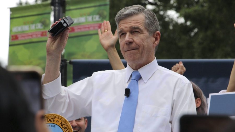 North Carolina Gov. Roy Cooper holds up his veto stamp before affixing it to a bill.